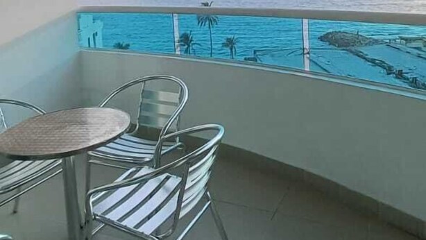 A balcony with a table and chairs, a ceiling fan, and a view of the ocean. - APARTAMENTO 702A (Cartagena)