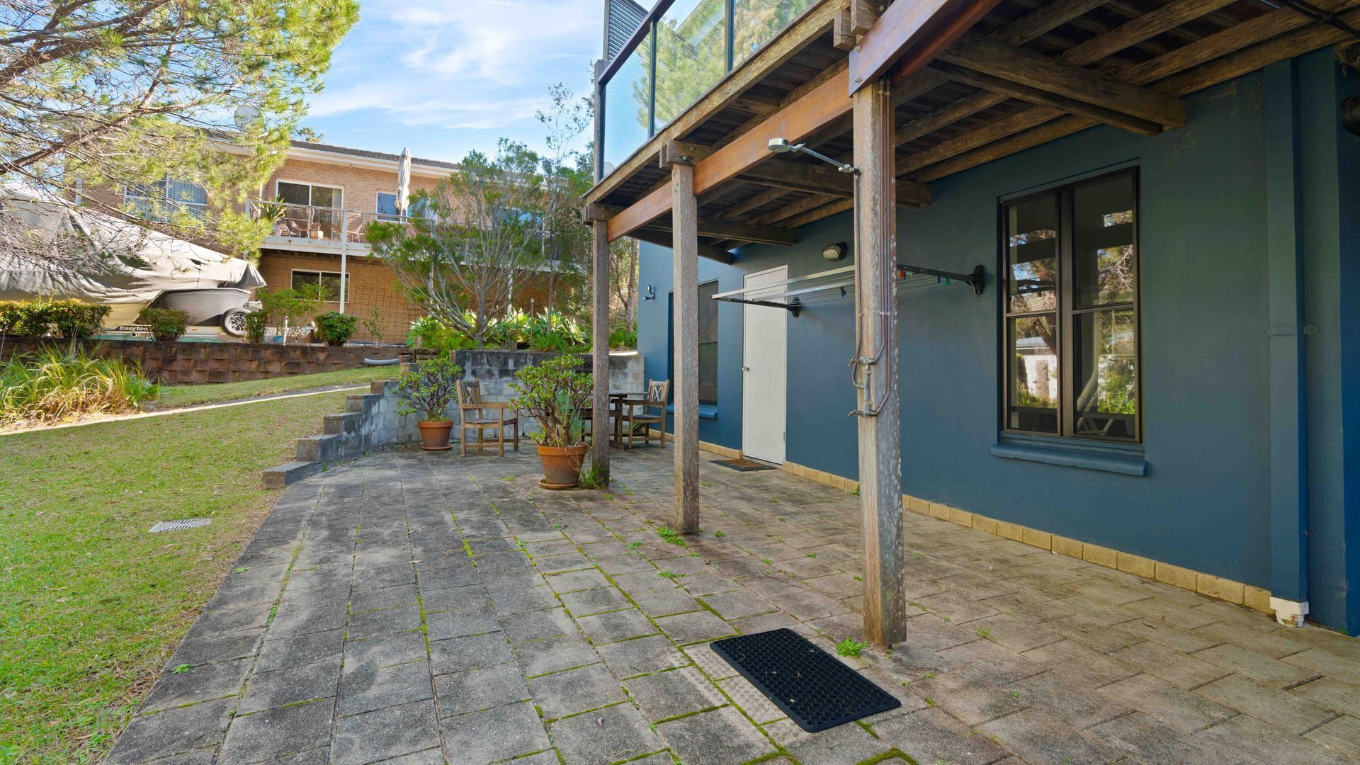 Una propiedad residencial con patio empedrado, mobiliario exterior y puerta de garaje.