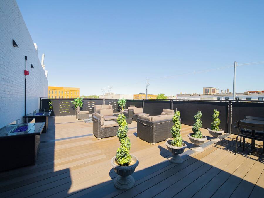 Une terrasse sur le toit, aménagée avec du mobilier d’extérieur, des plantes en pot et offrant une vue dégagée sur le paysage urbain.