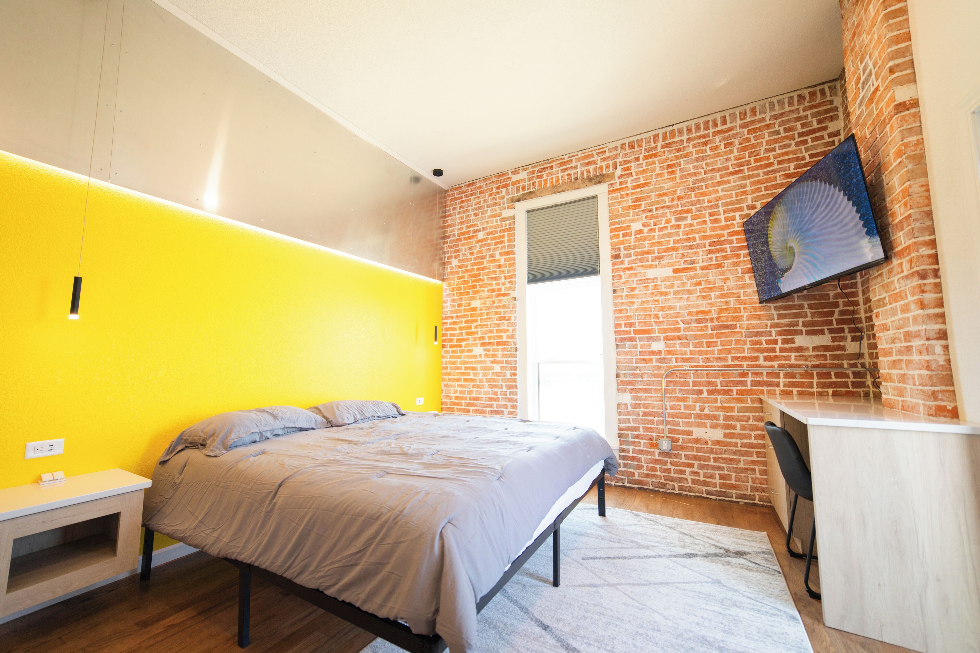A bedroom with a bed, a desk, and a chair.