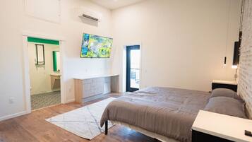 A bedroom with a large bed, a desk, and a painting on the wall.