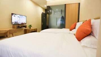Camera d'albergo con un letto, una TV, una scrivania e una porta in vetro che dà su un angolo doccia.