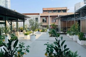 An outdoor courtyard with potted plants, a covered seating area, and a modern building in the background. - Nandu Hotel (Chengdu Renmin South Road Us Consulate) (Chengdu)