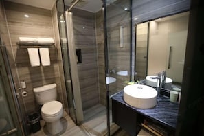 A modern bathroom with a glass shower enclosure, a toilet, and a vanity with a large mirror. - Nandu Hotel (Chengdu Renmin South Road Us Consulate) (Chengdu)