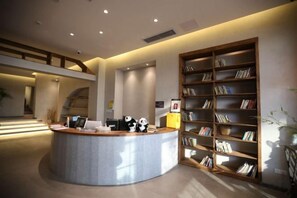 A reception area with a curved desk, a bookshelf, and a staircase in the background. - Nandu Hotel (Chengdu Renmin South Road Us Consulate) (Chengdu)