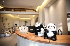 Un comptoir d’accueil orné de peluches en forme de panda, un comptoir en bois et un aménagement intérieur moderne.
