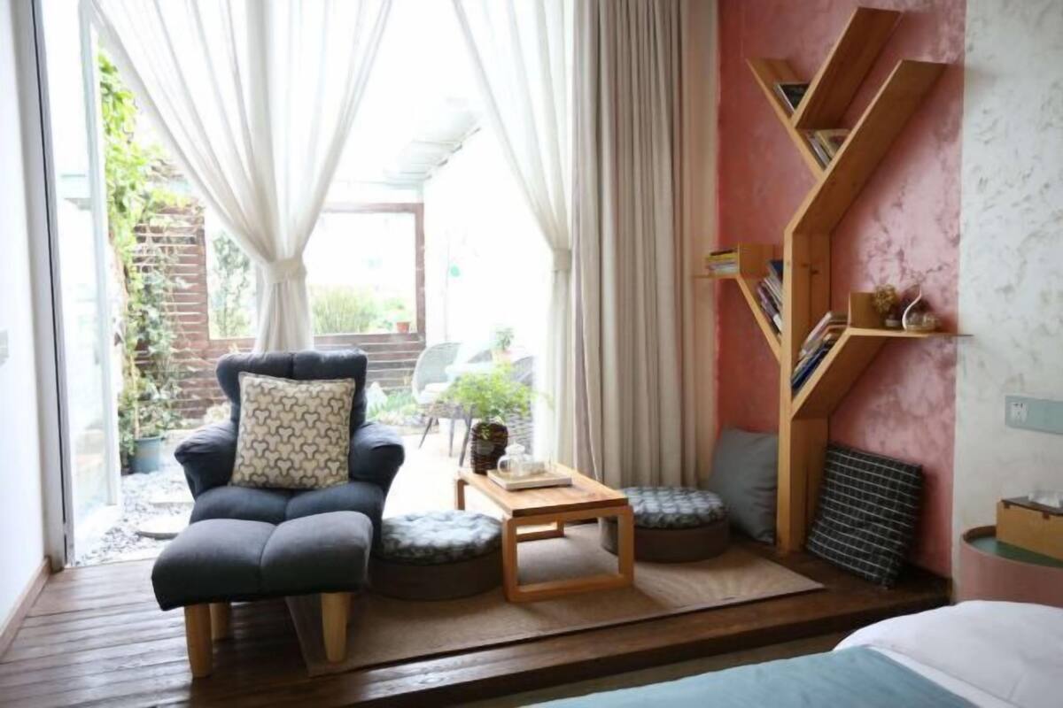 A cozy room with a sofa, ottoman, and a bookshelf.