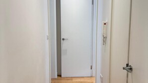 A hallway with a wooden floor leading to a white door with a handle and a keyhole. - Central London Apartment With 2 Bedrooms -sleeps 6 (London)