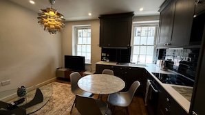 A modern kitchen with dark cabinets, a round dining table, and a large window. - Central London Apartment With 2 Bedrooms -sleeps 6 (London)