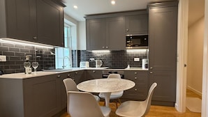 A modern kitchen with grey cabinets, a round marble table, and four white chairs. - Central London Apartment With 2 Bedrooms -sleeps 6 (London)