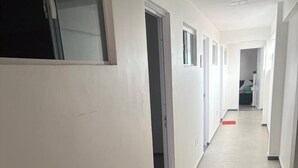 A long, narrow hallway with white walls and a tiled floor. - Hospedagem Praia do Forte (Tamandaré)