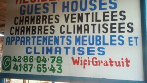 En skylt som listar olika typer av boenden, till exempel ”RESIDENCE FIFA GUEST HOUSES” och ”CHAMBRES VENTILEES”.