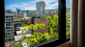 Vista dalla finestra su una città con edifici moderni, tra cui un'imponente costruzione a più piani.