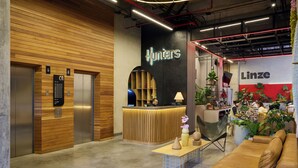 Una zona de recepción con un mostrador de madera, una recepción y un cartel que dice 'Hunters', y un cartel que dice 'Linze'.