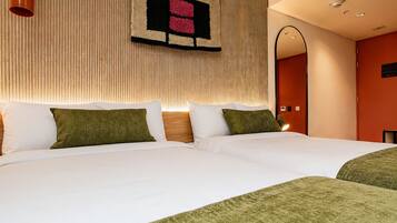 Habitación de hotel con dos camas, una obra de arte en la pared, un espejo y una lámpara en el techo.