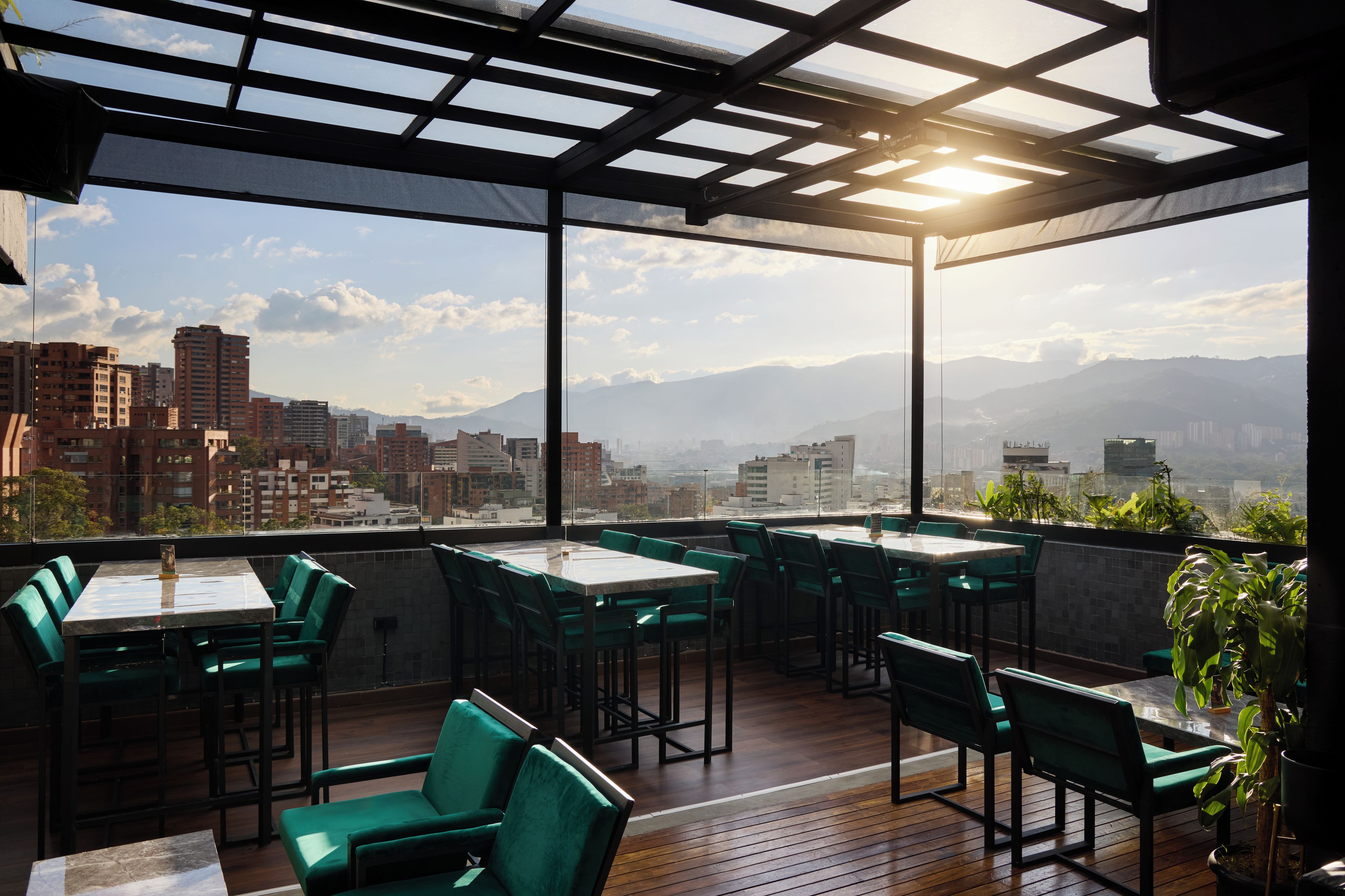 Terraza en la azotea con mesas y sillas, con vistas a la ciudad.