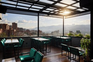 Terraza en la azotea con mesas y sillas, con vistas a la ciudad.