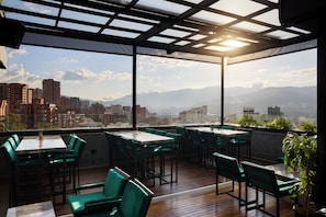 Une terrasse sur le toit, aménagée avec des tables et des chaises, offrant une vue sur la ville.