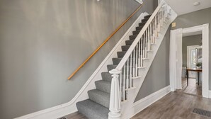 A staircase with a white balustrade and grey carpeted steps leading to a landing.