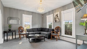 A modern living room with a sectional sofa, a round coffee table, and a chandelier.