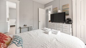 A modern bedroom with a large bed, a television, and a dresser. - Modern 2BR • Mins to Univ, Zoo, Destiny & Downtown (Syracuse)