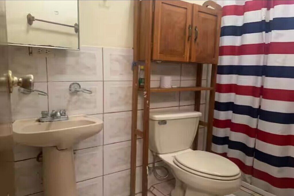 A bathroom with a white sink, wooden cabinet, toilet, and striped shower curtain.