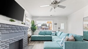 Un salon moderne avec une cheminée en pierre, un canapé de couleur turquoise et un ventilateur de plafond.