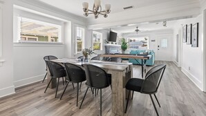 Une cuisine moderne avec un îlot central en bois, des chaises noires et un lustre.