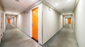Een lange, smalle hotelgang met vloerbedekking en witte wanden.