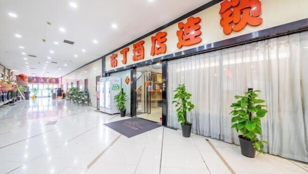 Een hotelingang met een bord in Chinese karakters, plantenbakken en een schone, betegelde vloer.