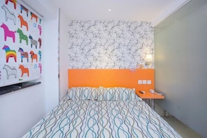 Ein Schlafzimmer mit einem gemusterten Bettüberwurf, einem Wandbild von Pferden und einer Wandtapete mit Muster.
