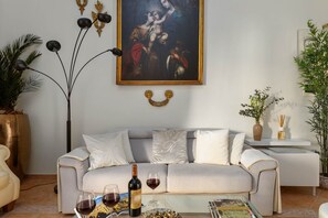 Ein Wohnzimmer mit einer Couch, einem Gemälde, einer Weinflasche und einer Vase.