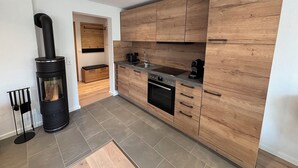 A modern kitchen with wooden cabinets, a built-in oven, and a black stove. - Exclusive 5-star vacation apartment in the heart of Bischofsgrün (Bischofsgrün)