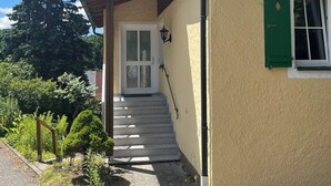 A building with a stone staircase leading to a door, surrounded by greenery and a clear blue sky. - Exclusive 5-star vacation apartment in the heart of Bischofsgrün (Bischofsgrün)