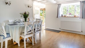 Un coin repas avec une table ronde, des chaises blanches et une fenêtre avec des rideaux.