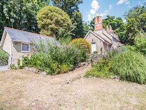 A stone house with a sloped roof and a garden path leading to it. - Lisle Combe Cottage (Ventnor)