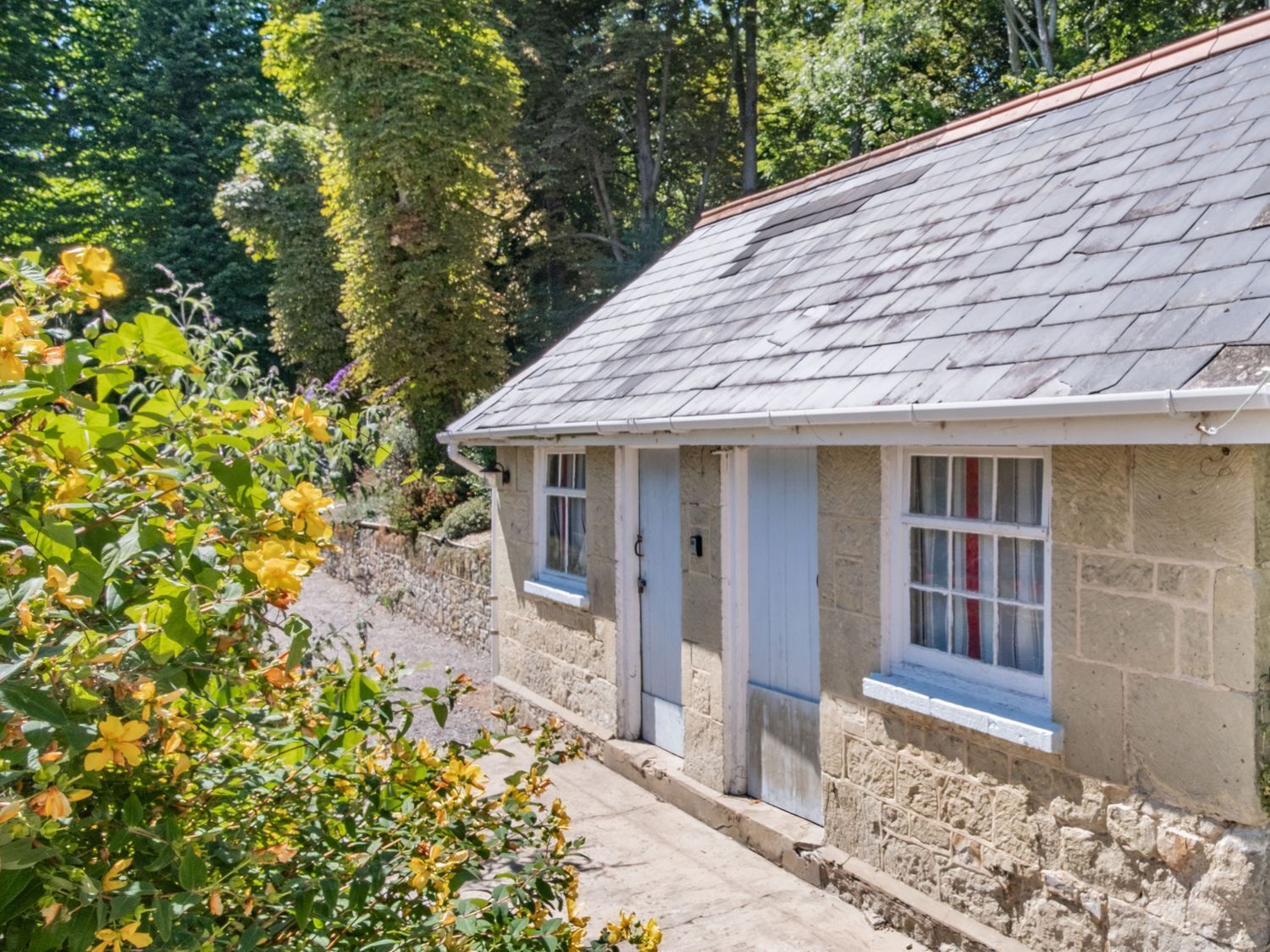 A stone cottage with a tiled roof, a small porch, and a window with a white frame.