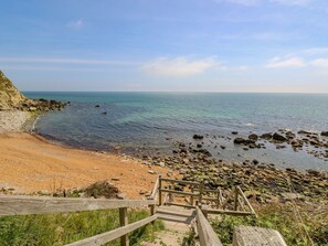 A wooden staircase leading to a beach with clear water and a sandy shore. - Lisle Combe Cottage (Ventnor)