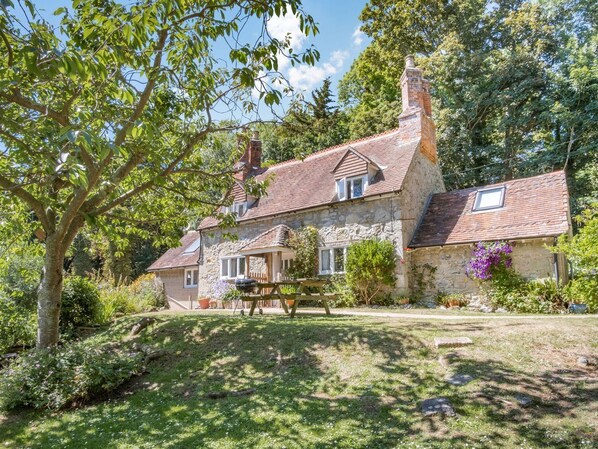A stone house with a tiled roof, a chimney, and a small porch. - Lisle Combe Cottage (Ventnor)