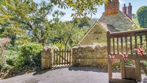 Une petite maison en pierre avec une pancarte indiquant « Fishcombe Cottage ».