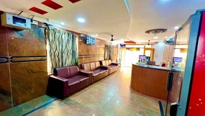 A hotel lobby with a reception desk, leather sofas, and a marble wall. - Hotel Govind Heights (Tirupati)