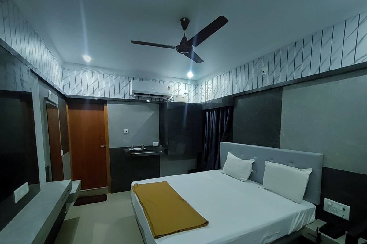 A modern hotel room with a bed, bedside table, and a ceiling fan.