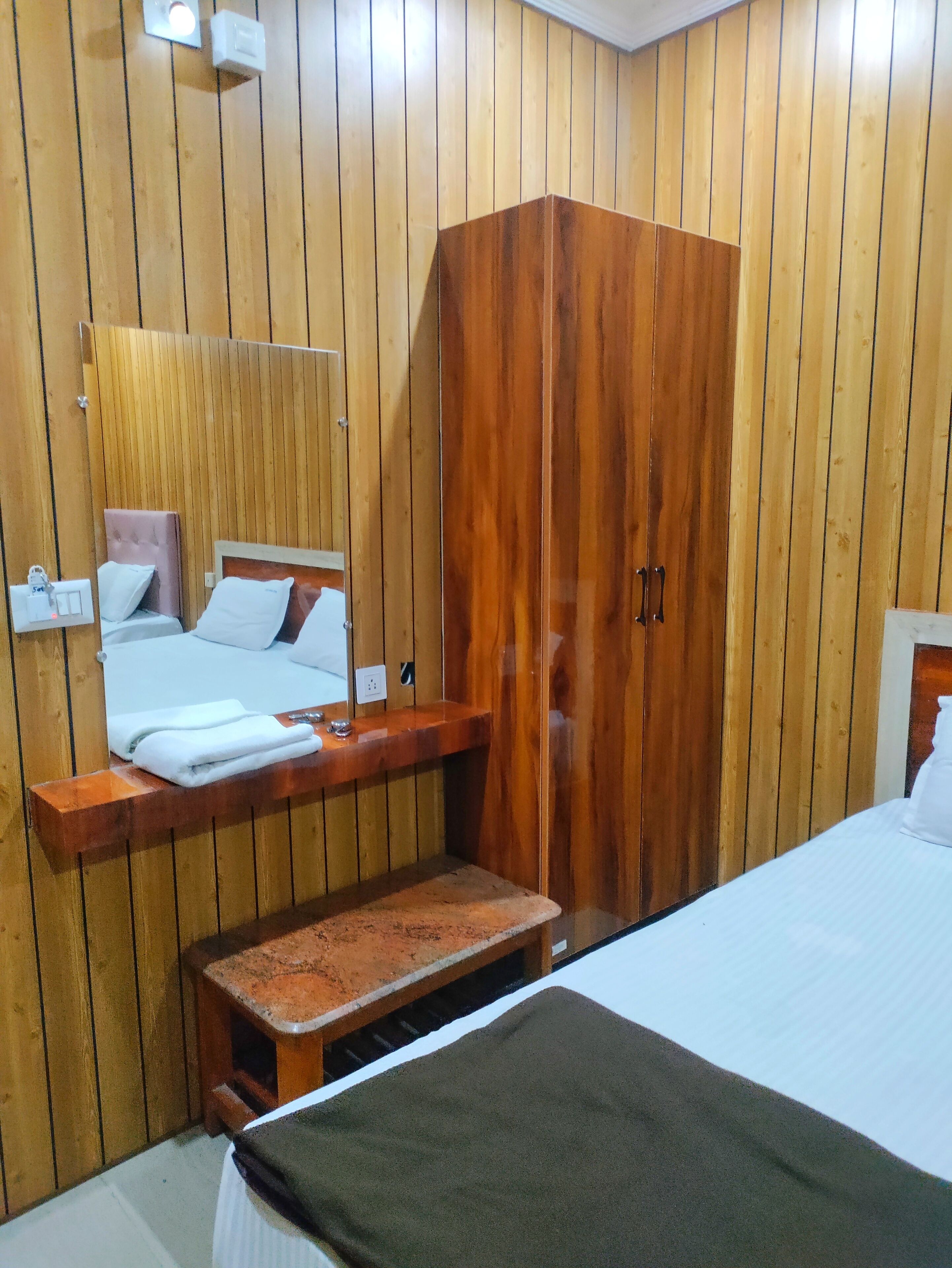 A wooden-paneled room with a bed, a bench, a wardrobe, and a mirror.