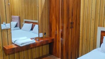 A wooden-paneled room with a bed, a bench, a wardrobe, and a mirror.