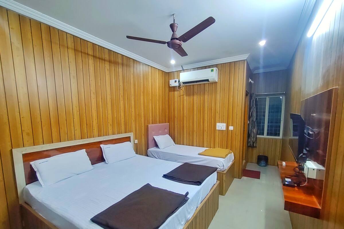 A hotel room with two beds, a ceiling fan, an air conditioning unit, and a television.