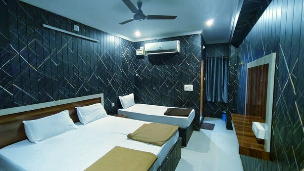 A hotel room with two beds, a ceiling fan, an air conditioning unit, and a mirror. - Hotel Govind Heights (Tirupati)