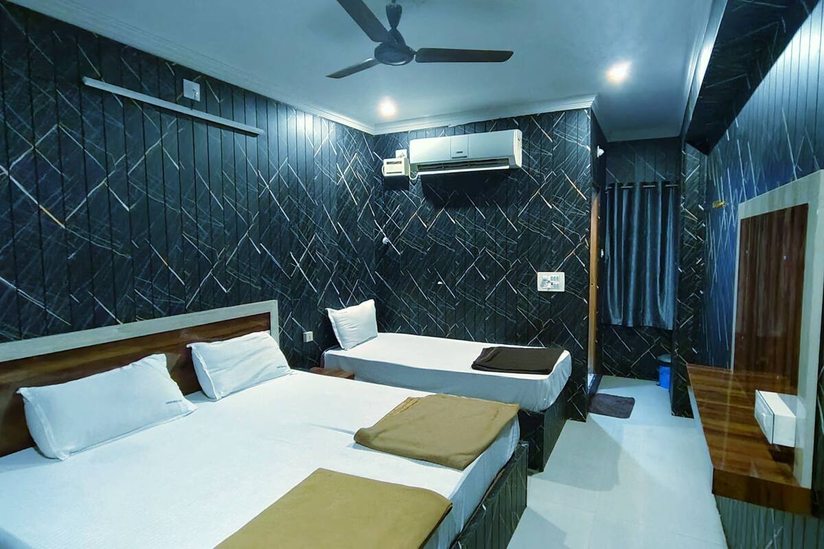 A hotel room with two beds, a ceiling fan, an air conditioning unit, and a mirror.