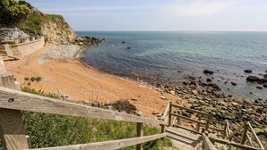 A coastal beach with a wooden staircase leading down to the shore. - Swallows (Ventnor)