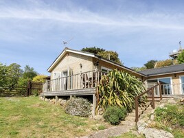 A two-story house with a balcony, a wooden fence, and a garden with various plants.