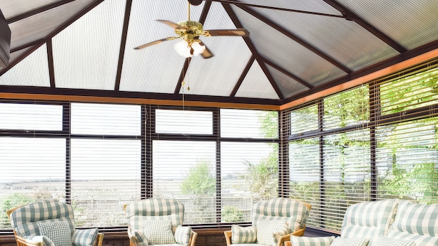 A sunroom with wicker furniture, large windows, and a ceiling fan. - Cae Coch (Brynteg)